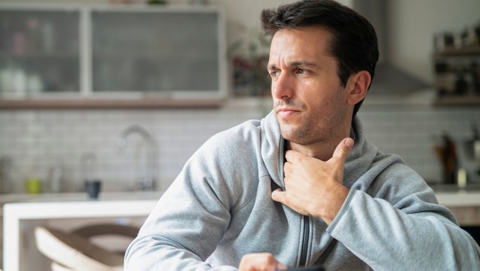 Man in a hoodie sits, considering